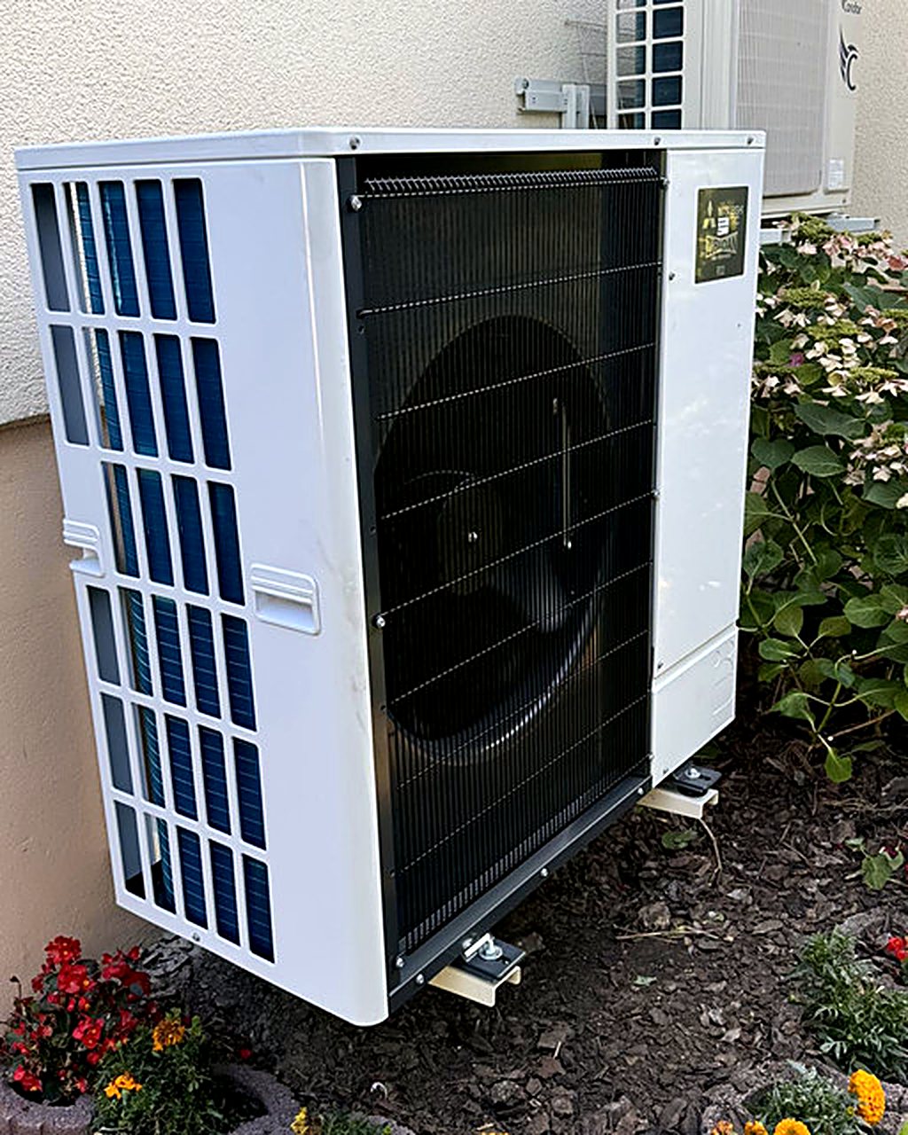 Unité extérieure de climatisation réversible installée dans un jardin par AIS Chauffage